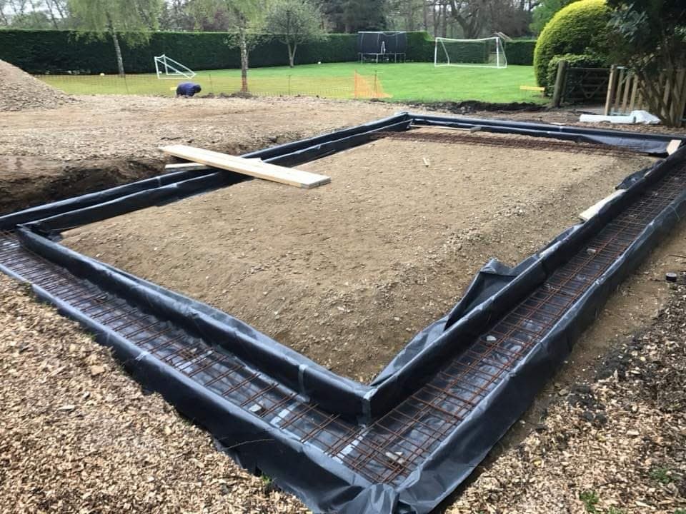 Foundation trenches lined with membrane and steel reinforcement, ready for concrete