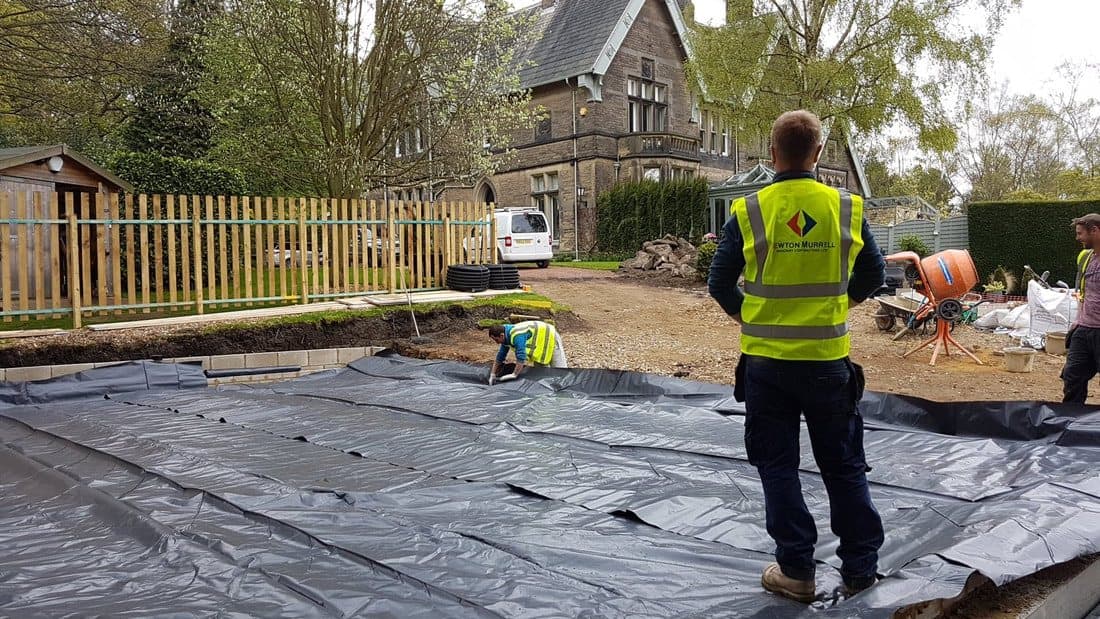 Damp-proof membrane being laid across the floor area, with the Victorian house behind