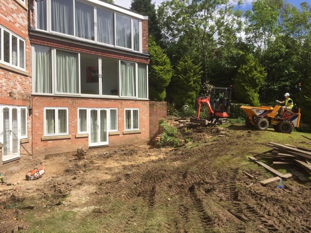 Groundworks under way, with a mini digger and dumper behind the house