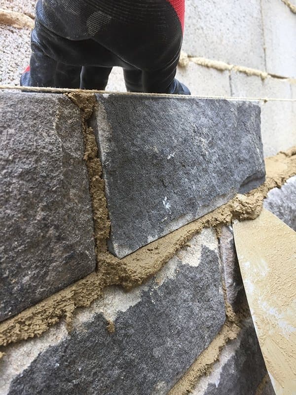 Stone being bedded on mortar against a string line